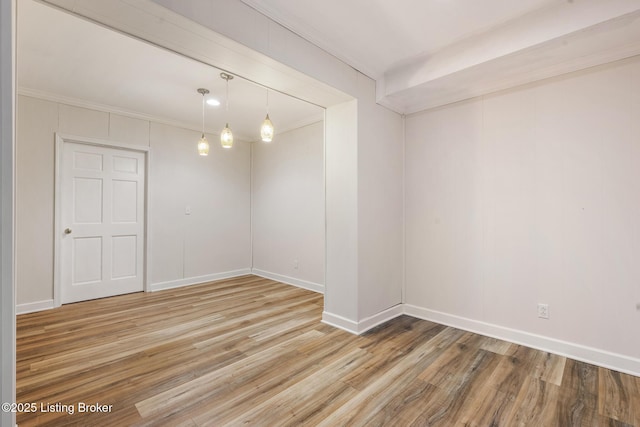 spare room featuring light wood-type flooring, crown molding, and baseboards