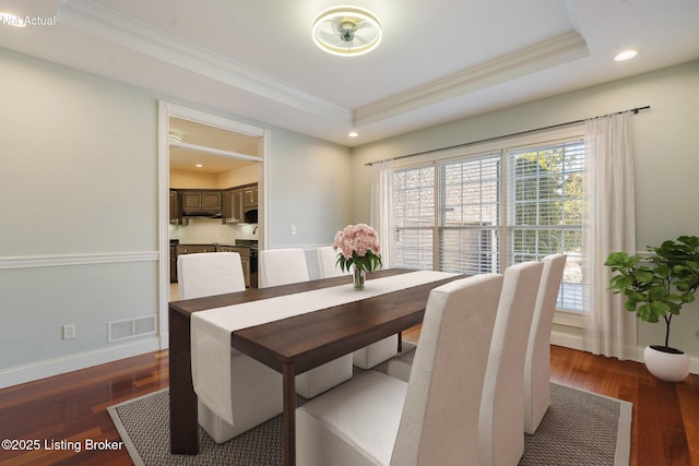 dining space featuring crown molding, a tray ceiling, and dark hardwood / wood-style floors