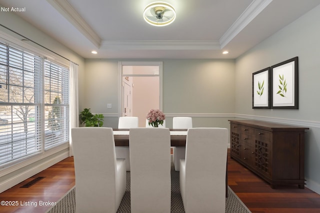 dining room with crown molding, a tray ceiling, and dark hardwood / wood-style floors