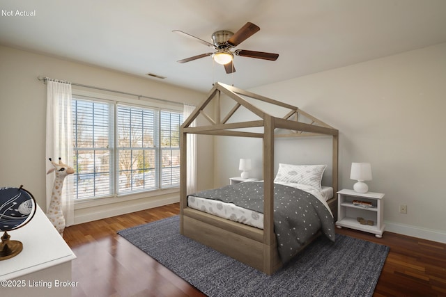 bedroom with a ceiling fan, wood finished floors, visible vents, and baseboards