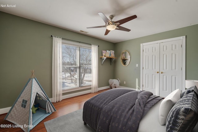 bedroom with visible vents, baseboards, a ceiling fan, wood finished floors, and a closet