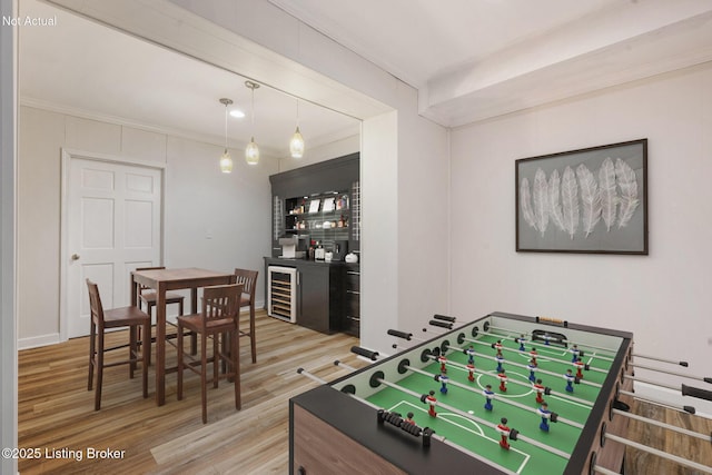 playroom with hardwood / wood-style floors, crown molding, wine cooler, and bar area