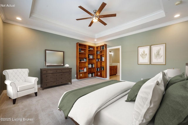 bedroom with a raised ceiling, ceiling fan, light colored carpet, and ensuite bath