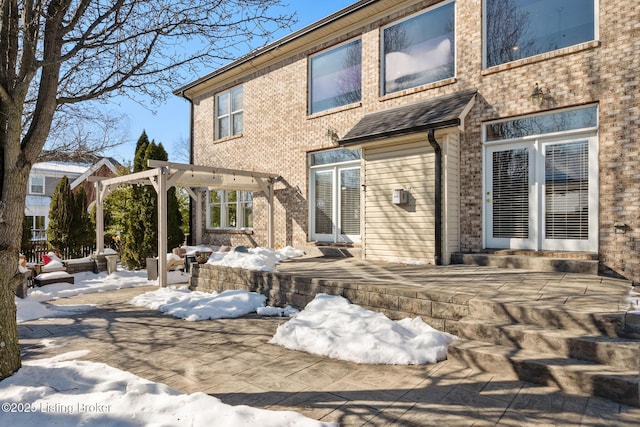 snow covered rear of property with a pergola and a patio area