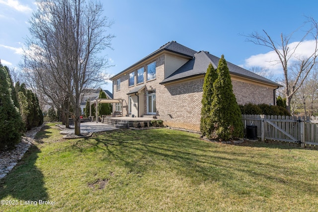 rear view of house with a patio, a gate, fence, a yard, and brick siding