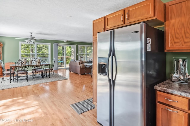 kitchen with light hardwood / wood-style floors, stainless steel refrigerator with ice dispenser, ceiling fan, a textured ceiling, and crown molding