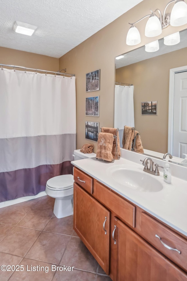 bathroom with toilet, vanity, tile patterned flooring, and a textured ceiling