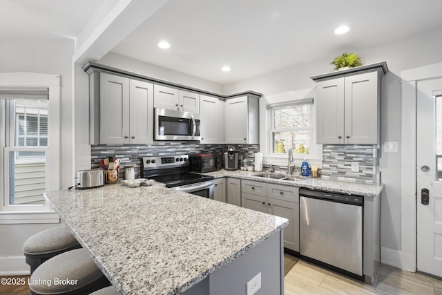 kitchen featuring backsplash, appliances with stainless steel finishes, sink, and gray cabinetry