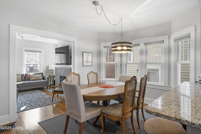 dining room featuring a brick fireplace and dark hardwood / wood-style flooring