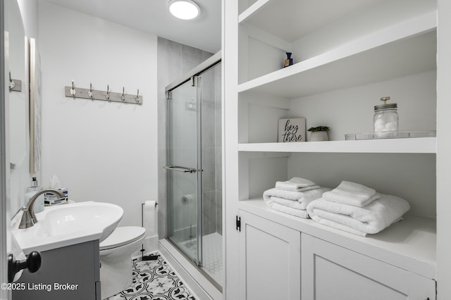 bathroom with vanity, a shower with door, and toilet