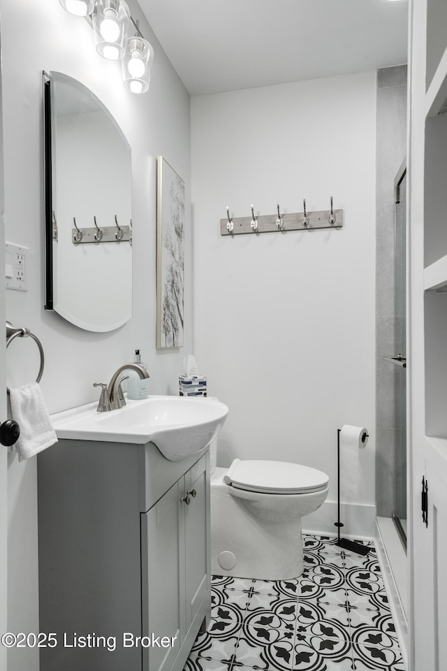 bathroom featuring tile patterned flooring, vanity, walk in shower, and toilet