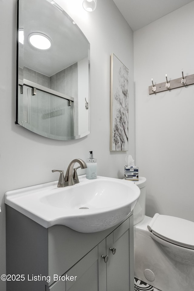 bathroom featuring vanity, an enclosed shower, and toilet