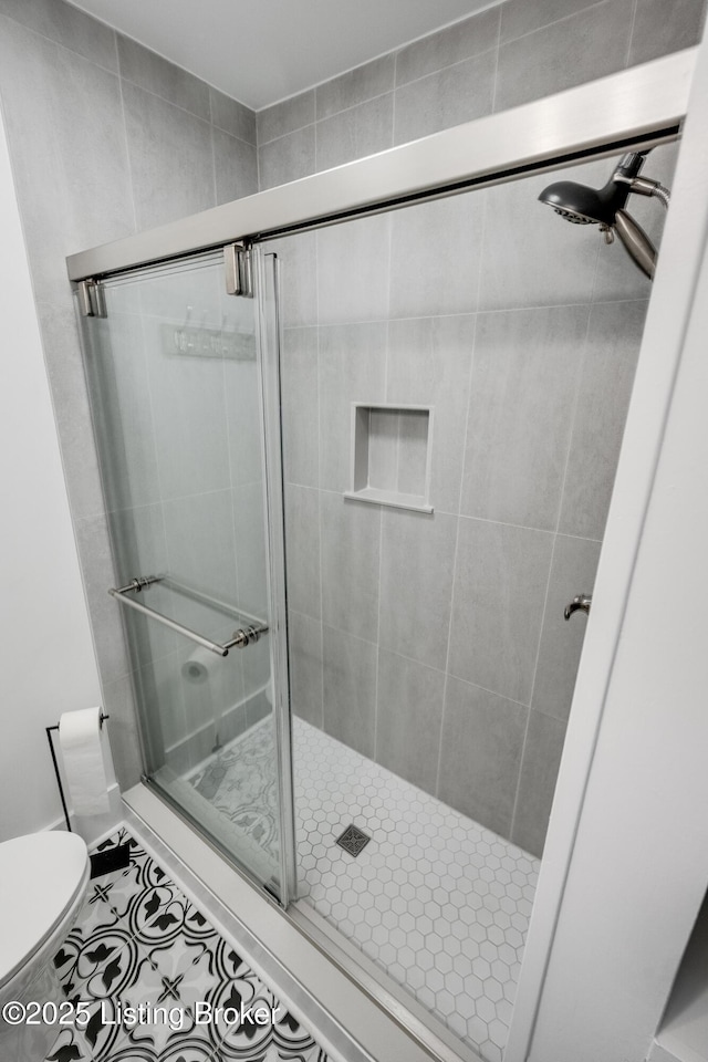 bathroom with tile patterned flooring, an enclosed shower, and toilet