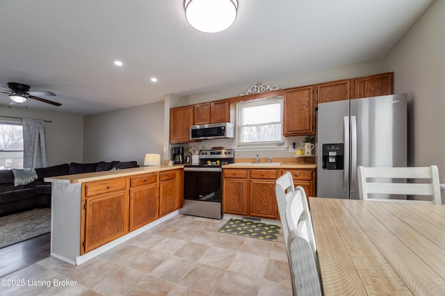 kitchen featuring ceiling fan, sink, appliances with stainless steel finishes, and kitchen peninsula