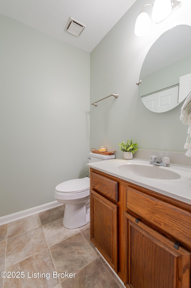 bathroom featuring a textured ceiling, toilet, and vanity