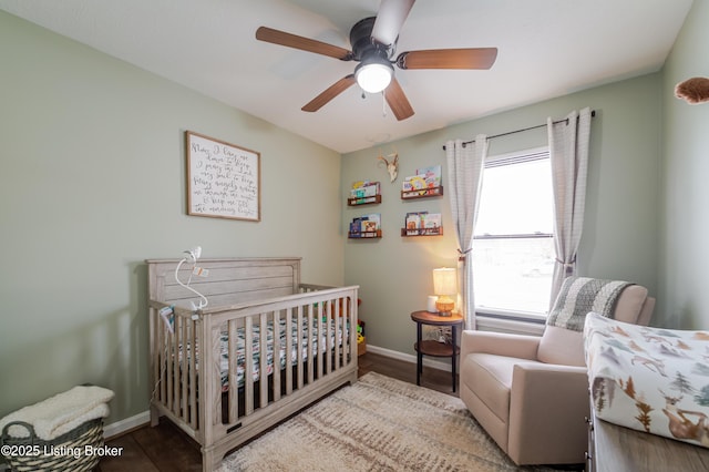 bedroom featuring ceiling fan, multiple windows, hardwood / wood-style floors, and a nursery area