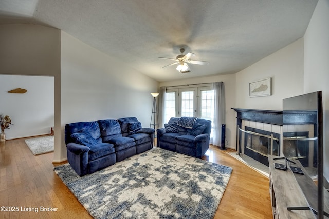 living room with hardwood / wood-style flooring, a fireplace, vaulted ceiling, and a textured ceiling