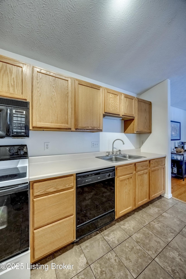 kitchen featuring sink, light brown cabinets, a textured ceiling, and black appliances