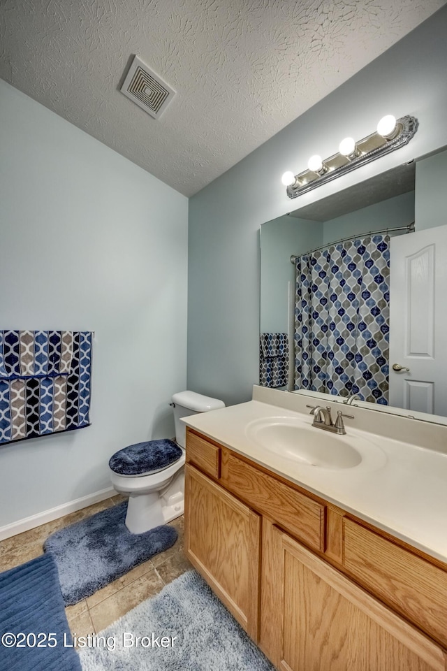 bathroom featuring vanity, tile patterned floors, a textured ceiling, and toilet