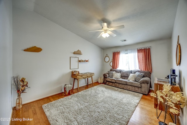 living room featuring ceiling fan, lofted ceiling, and light wood-type flooring