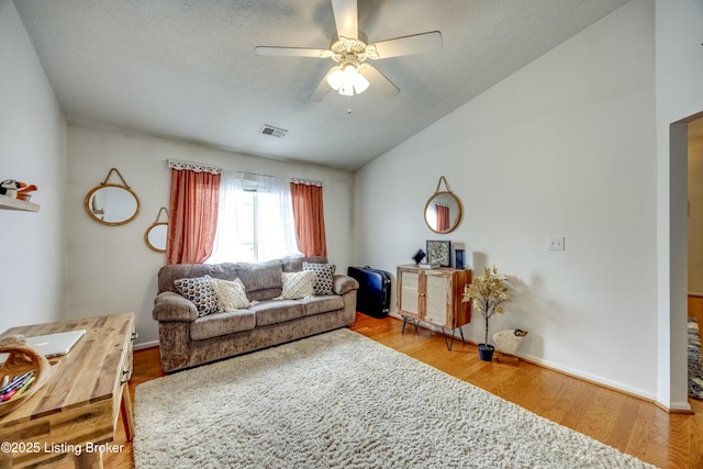 living room with lofted ceiling, ceiling fan, wood-type flooring, and a textured ceiling