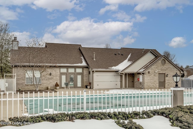 rear view of property featuring a fenced in pool and a patio