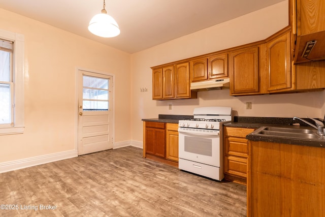 kitchen featuring decorative light fixtures, sink, gas range gas stove, and light hardwood / wood-style floors