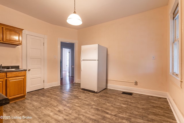 kitchen with hanging light fixtures, white refrigerator, and dark wood-type flooring