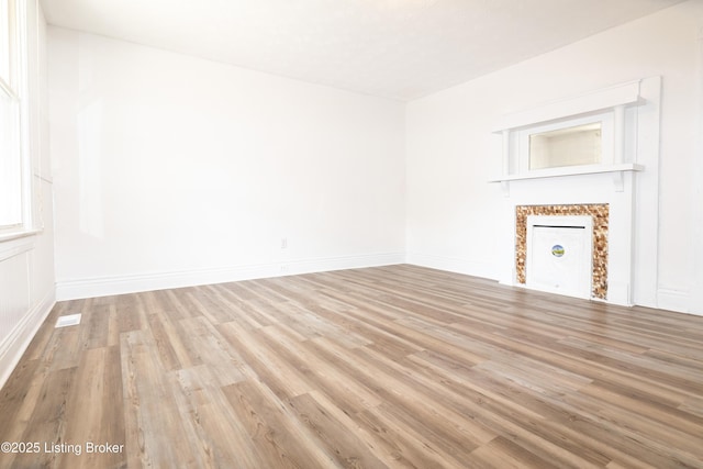 spare room with a fireplace and light hardwood / wood-style flooring