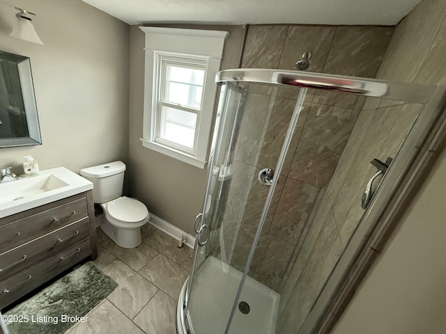 bathroom with baseboards, toilet, a stall shower, marble finish floor, and vanity