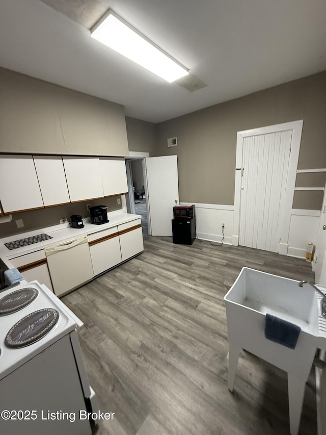 kitchen featuring visible vents, wood finished floors, white cabinetry, white appliances, and light countertops