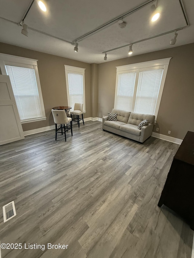 living room with track lighting, wood finished floors, visible vents, and baseboards