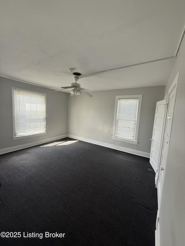 unfurnished room featuring baseboards, dark colored carpet, and ceiling fan