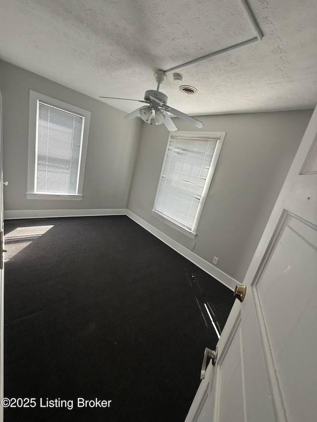 spare room featuring visible vents, baseboards, a textured ceiling, and a ceiling fan