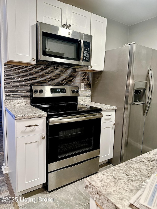 kitchen with backsplash, appliances with stainless steel finishes, and white cabinetry