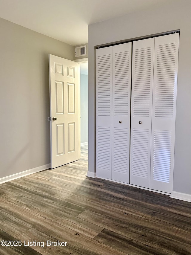 unfurnished bedroom featuring a closet and dark hardwood / wood-style floors