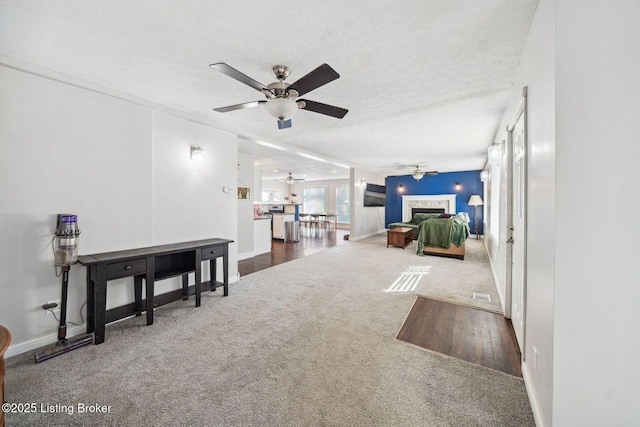 living room featuring ceiling fan, a textured ceiling, and dark carpet