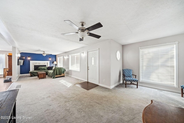 living room with ceiling fan, a textured ceiling, and carpet