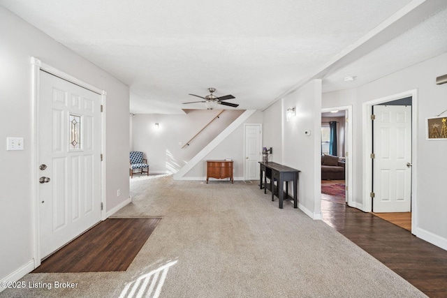 entrance foyer featuring dark carpet, a textured ceiling, and ceiling fan