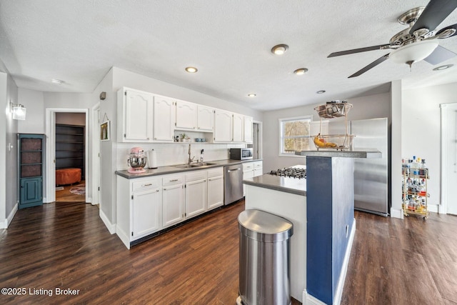 kitchen featuring a kitchen island, dark wood-type flooring, white cabinetry, and appliances with stainless steel finishes