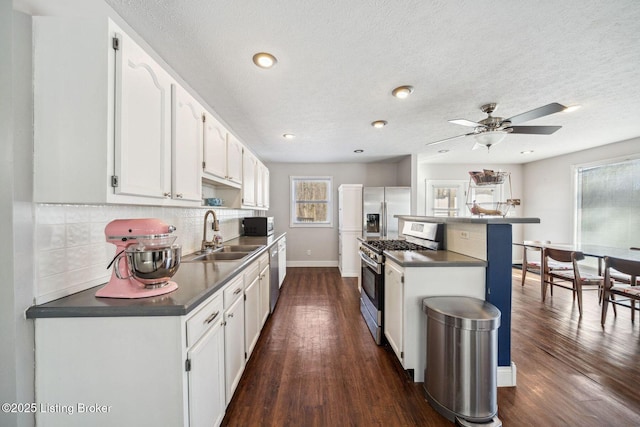 kitchen with tasteful backsplash, sink, white cabinets, stainless steel appliances, and dark hardwood / wood-style floors