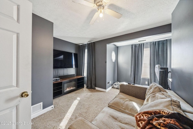 living room with light carpet, a textured ceiling, a fireplace, and ceiling fan