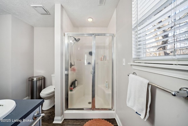 bathroom featuring a shower with shower door, toilet, a textured ceiling, wood-type flooring, and vanity