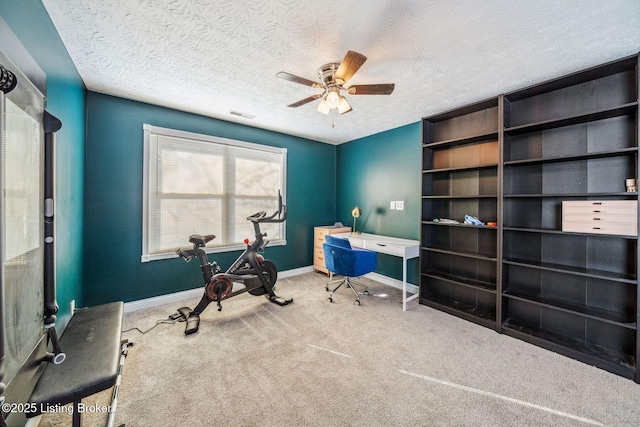 carpeted home office with ceiling fan and a textured ceiling