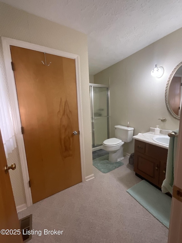 bathroom with vanity, a shower with door, toilet, and a textured ceiling