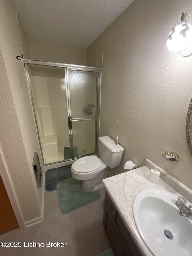 bathroom featuring vanity, a shower with shower door, and toilet