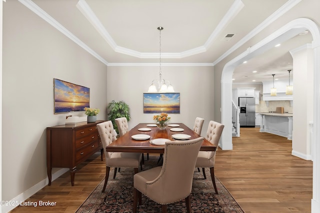 dining space with hardwood / wood-style flooring, a tray ceiling, and crown molding