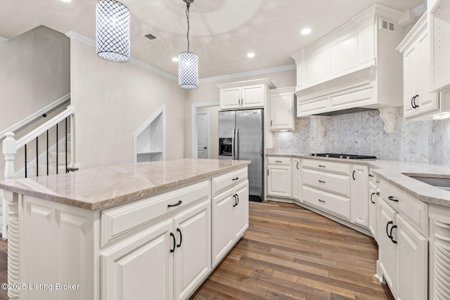 kitchen featuring decorative light fixtures, appliances with stainless steel finishes, a kitchen island, light stone countertops, and white cabinets