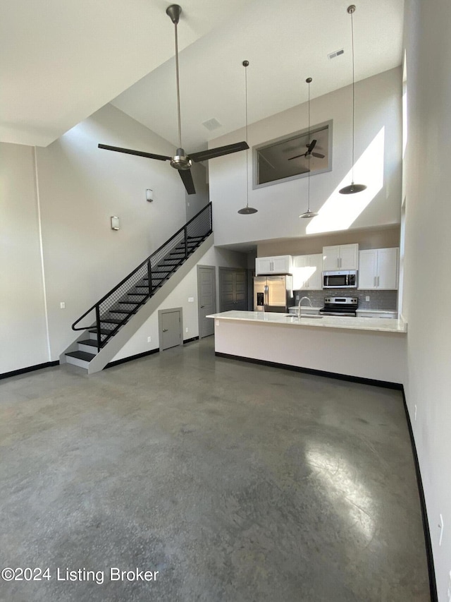 unfurnished living room featuring ceiling fan, a towering ceiling, and sink