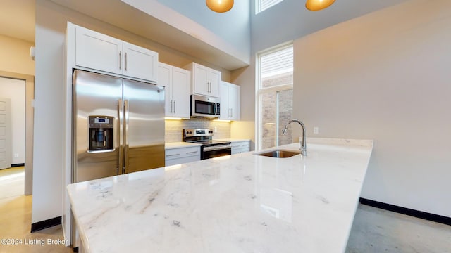 kitchen featuring backsplash, sink, white cabinetry, light stone countertops, and appliances with stainless steel finishes